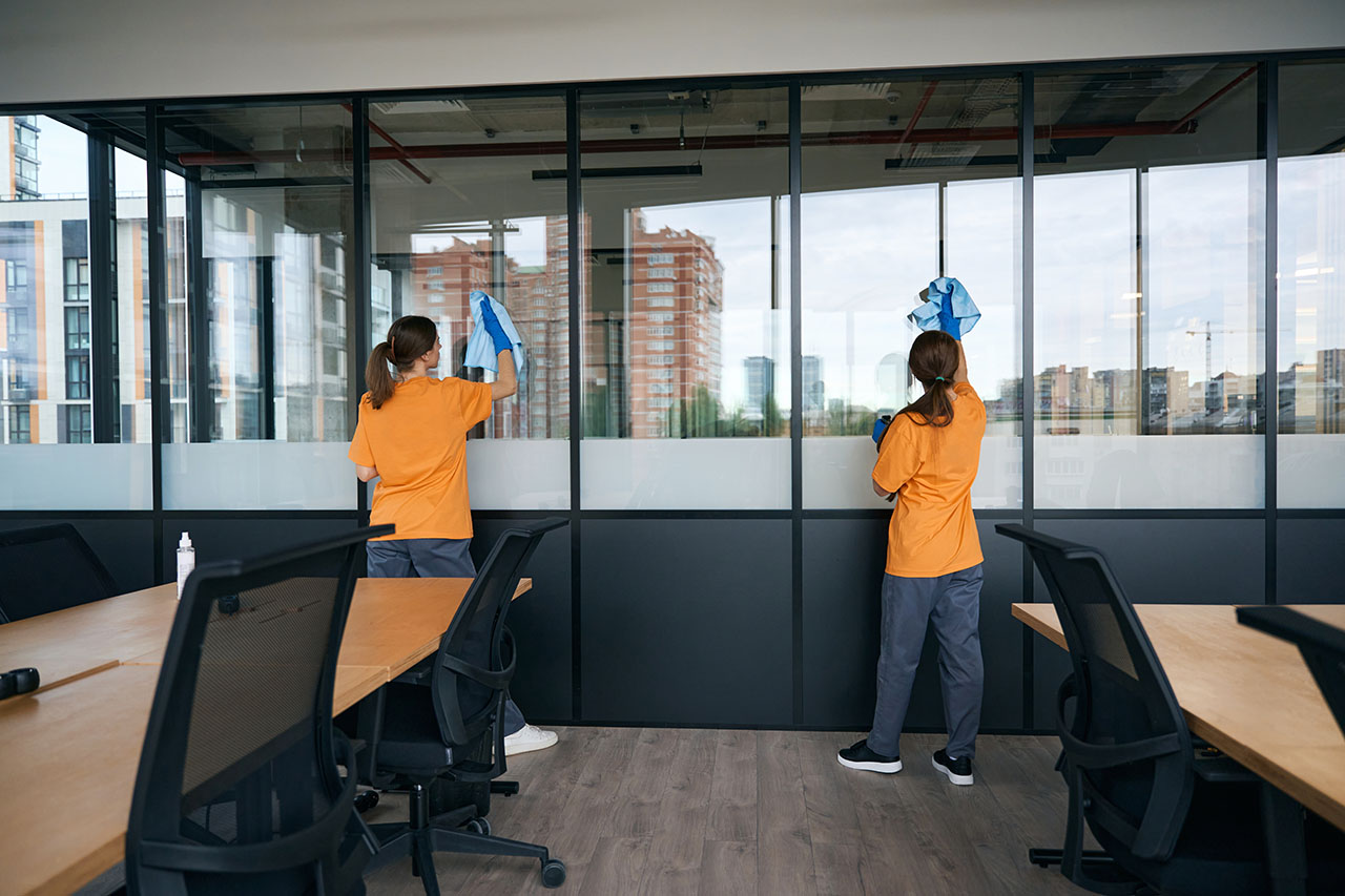 Two staff cleaning office windows at a job site